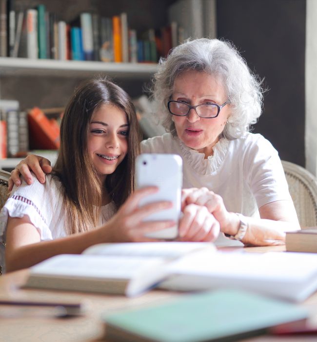 a grandmother sitting with her granddaughter and speaking with her estate planning attorney on the phone